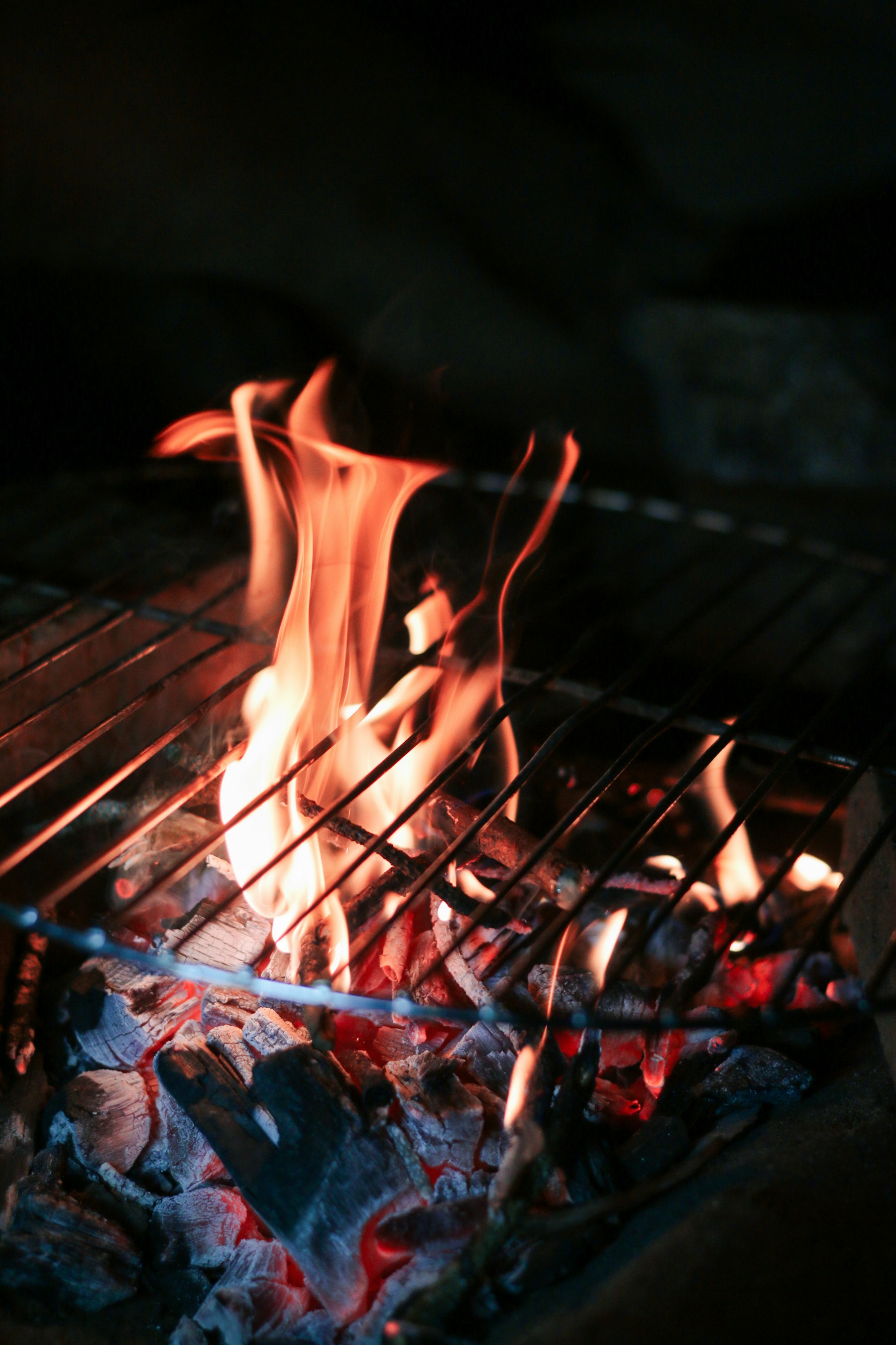焼き網の下で赤く熾った炭と炎